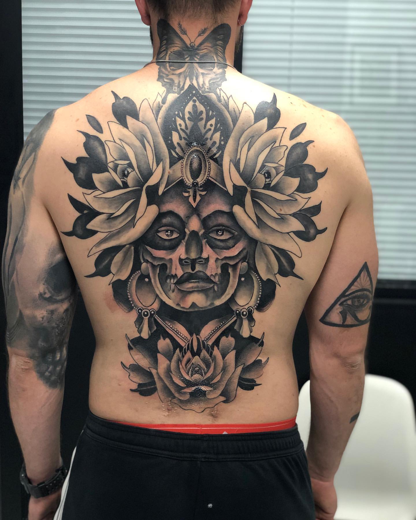 Large ornamental deity and lotus back piece tattoo in black and grey