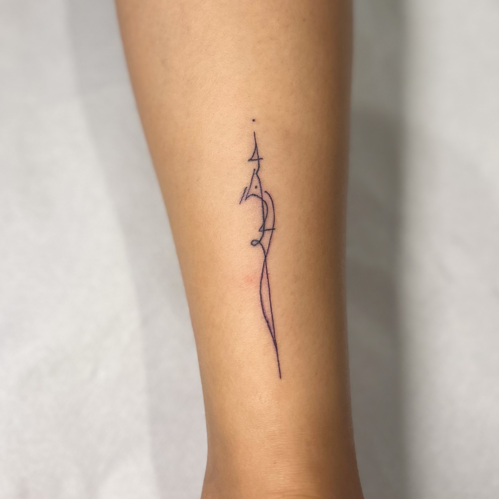 Minimal fine line dagger tattoo on a forearm